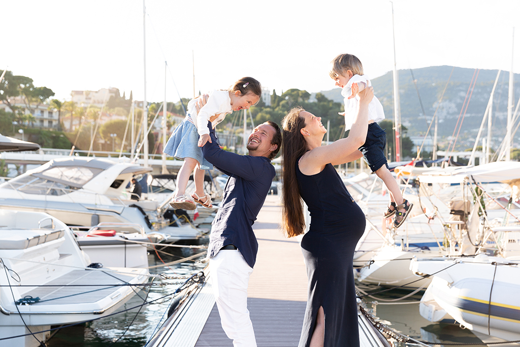 Une famille composée du papa, de la maman enceinte et de deux enfants pose sur un ponton du port de Saint Jean Cap Ferrat près de Nice. Photo prise par Myriam Ohayon Photographe