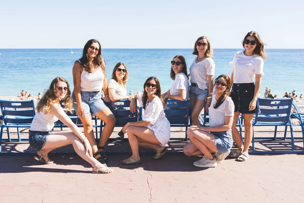 Future mariée et ses amies s'amusant sur les iconiques chaises bleues de la Promenade des Anglais lors d'un shooting EVJF à Nice.