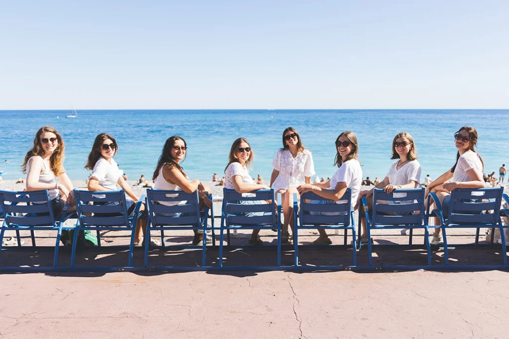 Groupe d'amies complices en séance photo EVJF sur la Promenade des Anglais à Nice face à la mer.