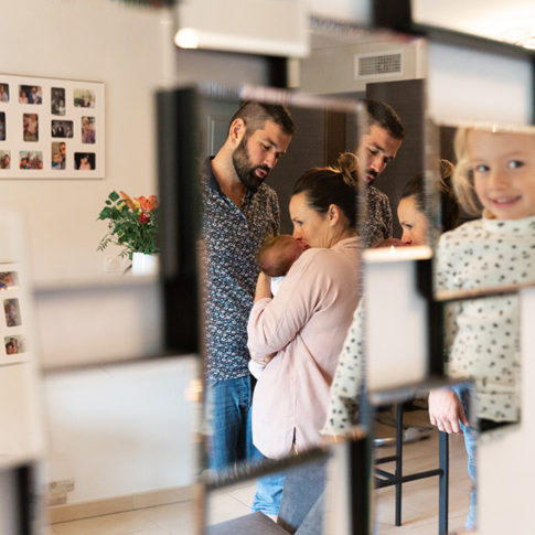 Photo d'une famille composée du papa, de la maman, d'une petite fille et du bébé. La photo est prise au travers d'un miroir. Myriam Ohayon Photographe