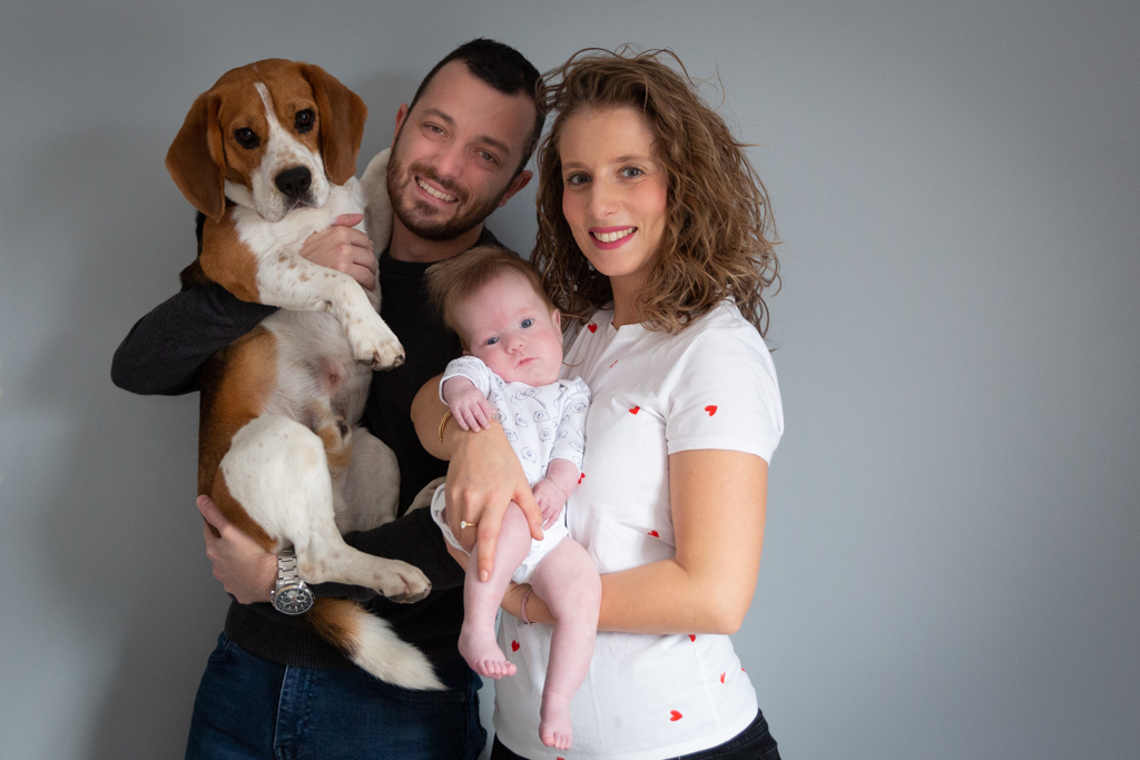 portrait d'une famille à l'occasion d'une séance photo naissance : le papa, la maman, le bébé et le chien beagle. Photo prise par Myriam Ohayon Photographe à Pégomas
