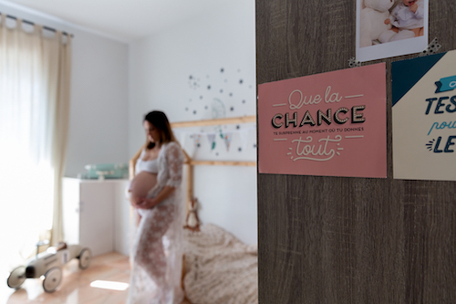 une femme enceinte pose dans la chambre de son futur bébé. Séance photo grossesse à domicile