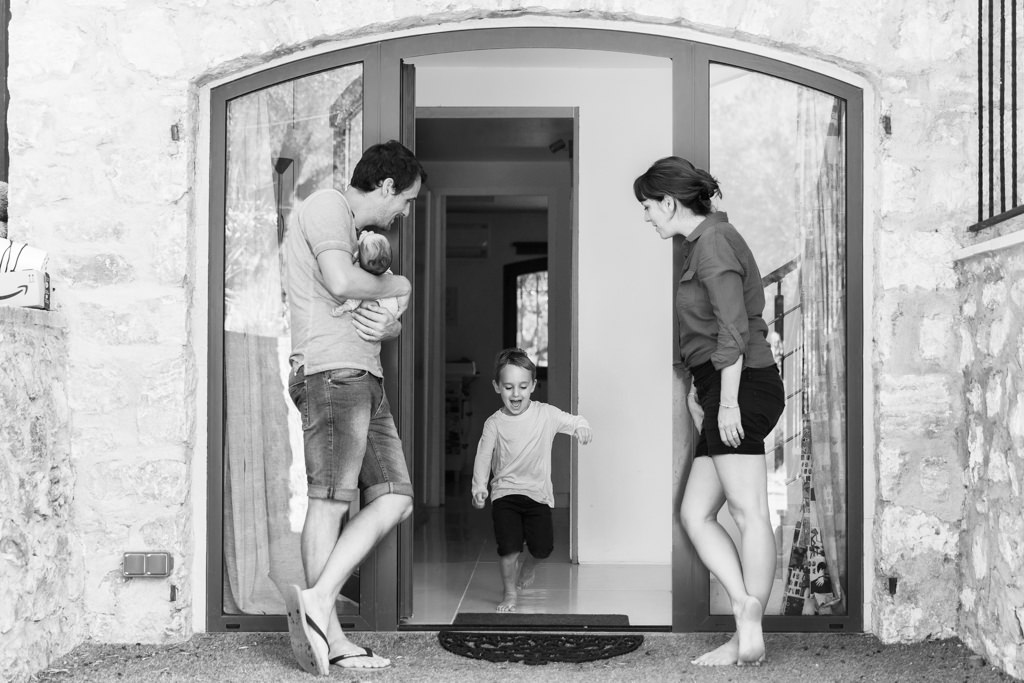 Un petit garçon de 7 ans court entre ses deux parents. Photo en noir et blanc. Photo prise par Myriam Ohayon Photographe au Rouret