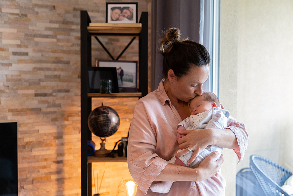 une maman tient son bébé dans ses bras. Photo prise lors d'un shooting naissance à domicile à Nice