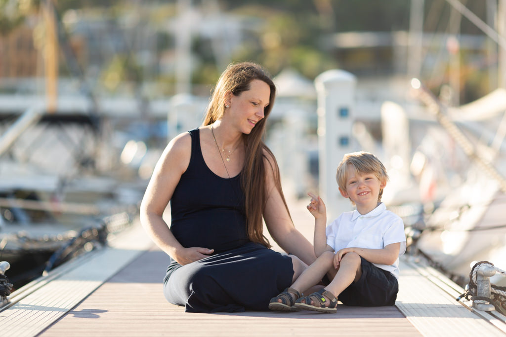une maman et son fils sont assis à la mer lors d'un shooting grossesse. Photo prise par Myriam Ohayon Photographe