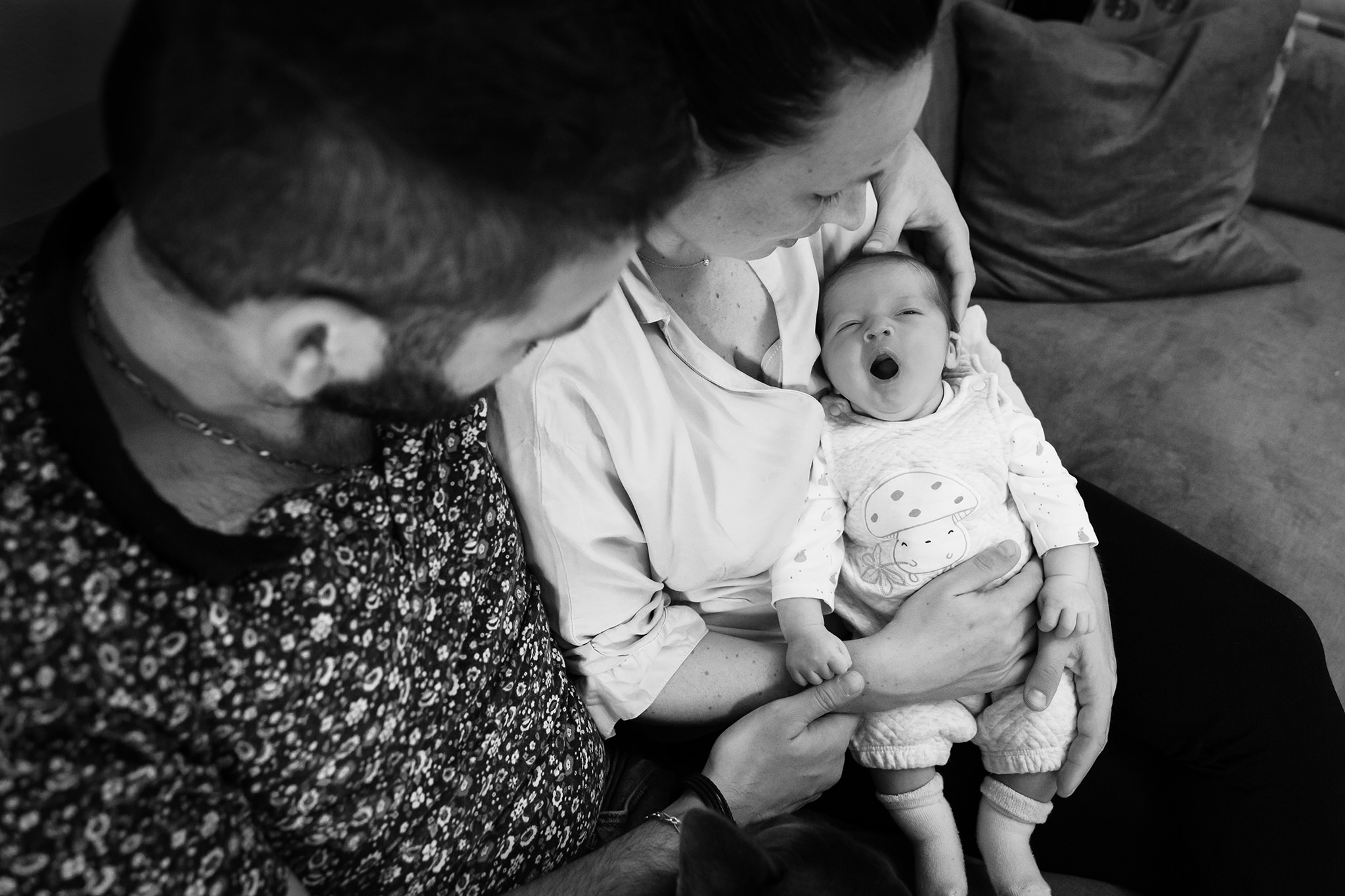 Un bébé baille dans les bras de ses parents lors d'une séance photo nouveau-né à Nice.
