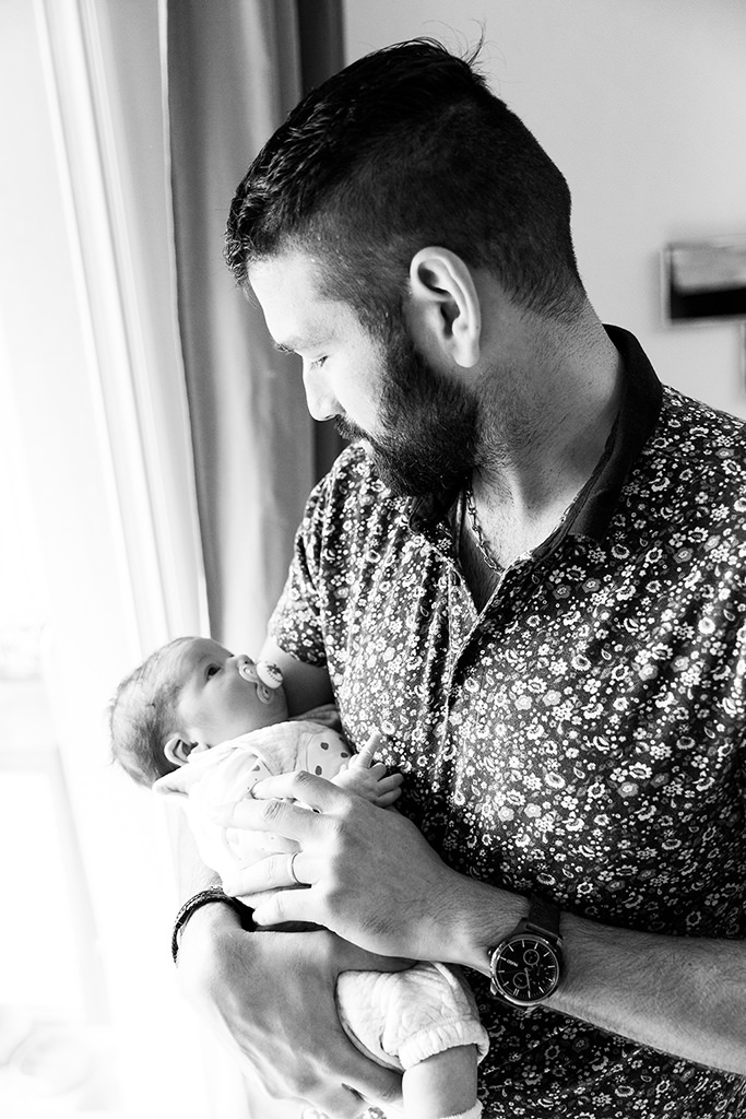 Un père et son nouveau-né se regardent tendrement. Photo prise lors d'un reportage naissance à domicile à Nice.