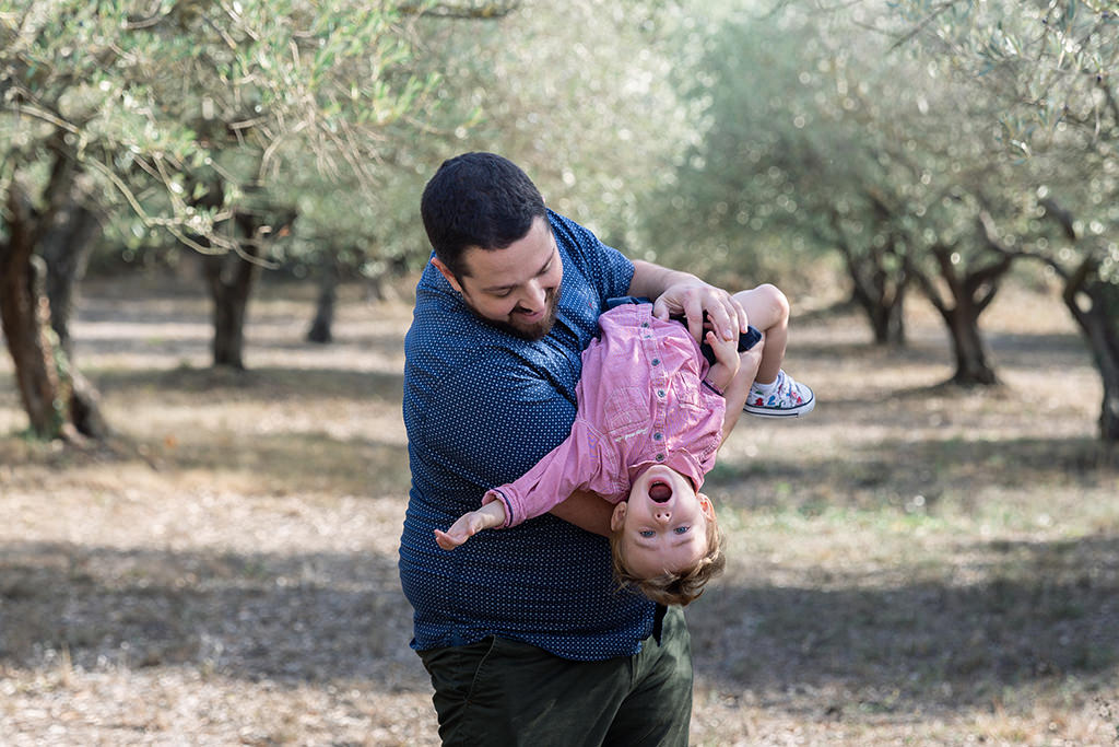Un papa s'amuse avec son fils lors d'une séance photo au coeurs des oliviers de Seillans.Myriam Ohayon Photographe