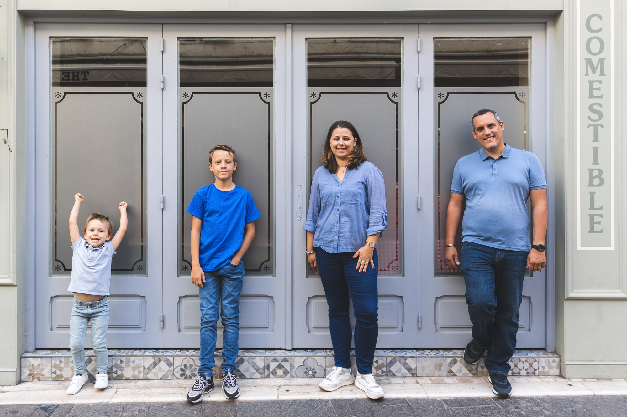 Séance photo en famille à Antibes : portrait d'une famille devant une façade d'un magasin.