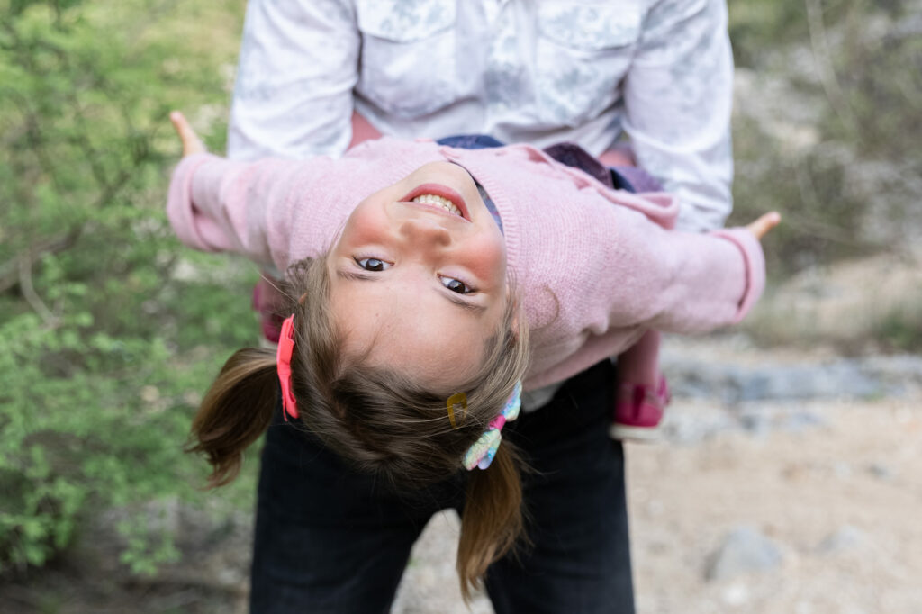 Séance photo en famille à Montauroux, près du lac de Saint-Cassien : une petite fille s'amuse dans les bras de son papa.