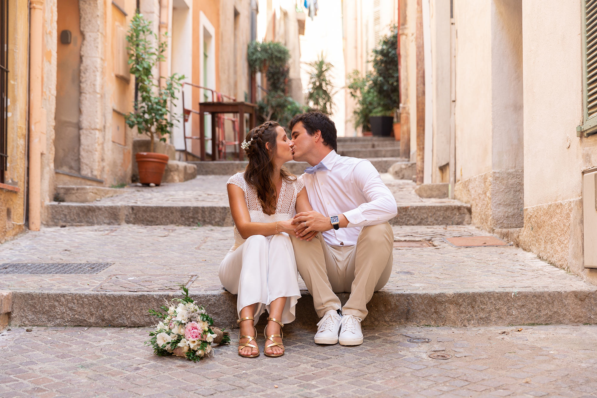 Un couple de mariés s'embrasse assis dans les ruelles de Villefranche sur mer.