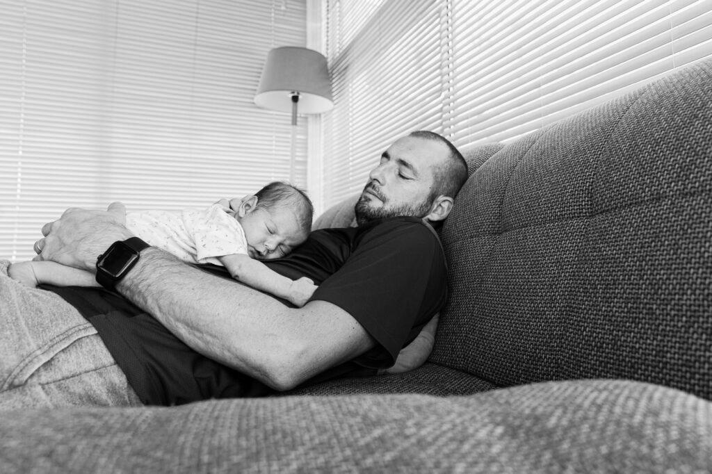Séance photo naissance à domicile à Nice : un père est endormi avec sa fille sur lui.