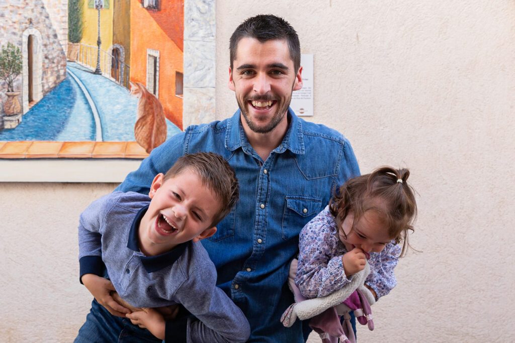 Séance photo famille à Tourrettes, Var. Un papa s'amuse avec ses deux enfants dans ses bras.