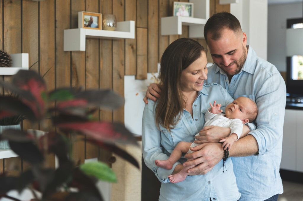 Un couple pose avec leur bébé durant une séance photo à domicile à Peymeinade.